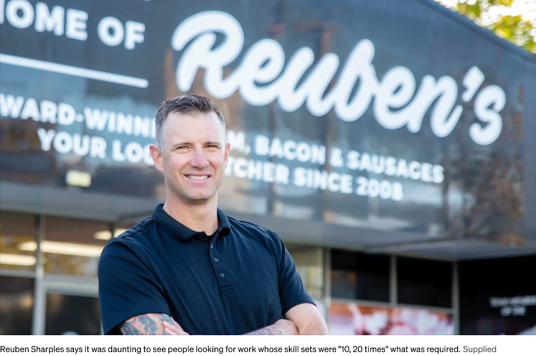 Reuben Sharples 站在肉鋪招牌前的照片
